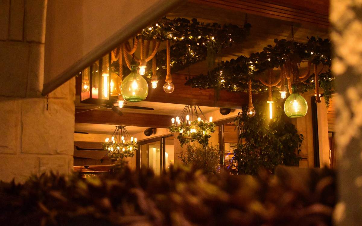 LED strip in a ceiling cove and track spotlights over a restaurant bar